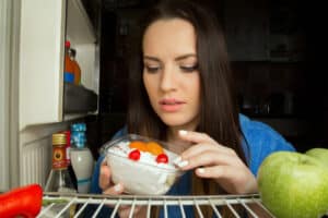 woman with dessert inside refrigerator