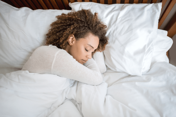 Woman sleeping peacefully in bed, representing the importance of quality sleep in managing PCOS symptoms