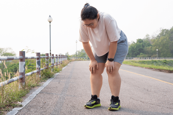 Woman bent over and tired after exercise – representing overexertion and energy crashes with PCOS