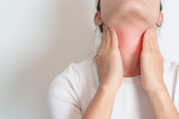Woman holding neck with red inflammation — representing thyroid issues and fatigue related to PCOS.