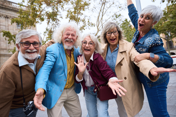 Group of joyful older adults smiling and laughing together outdoors, representing social connection and healthy aging