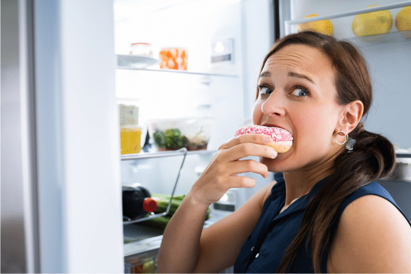 woman over 40 eating emotionally eating from refrigerator