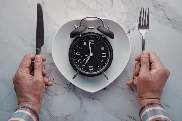 Clock on a plate representing meal timing and protein distribution across breakfast, lunch, and dinner.